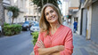 © Krakenimages.com - Smiling, confident mature woman with crossed arms standing on an urban street.