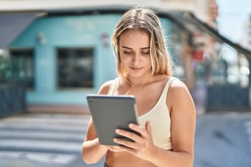 Poster - Young blonde woman smiling confident using touchpad at street