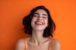 Beautiful young woman with curly hair, a beautiful young African American woman laughing on an orange background