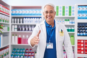 Canvas Print - Middle age grey-haired man pharmacist smiling confident shake hand at pharmacy