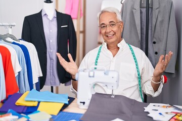 Canvas Print - Middle age man with grey hair dressmaker using sewing machine smiling cheerful with open arms as friendly welcome, positive and confident greetings