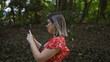 © Krakenimages.com - Smiling beautiful hispanic woman with glasses taking stunning picture at meiji temple, immersing in japanese culture using her smartphone technology, indulging in nature at green tokyo park.