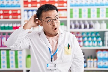 Poster - Chinese young man working at pharmacy drugstore in shock face, looking skeptical and sarcastic, surprised with open mouth