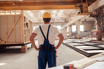 Wall Mural - Male builder in safety helmet observing building under construction