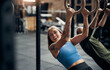 © Flamingo Images - Smiling woman working out on rings during a gym exercise class
