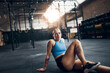 © Flamingo Images - Smiling young woman sitting on a gym floor after working out