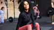 © Flamingo Images - Young woman sitting on weights at the gym