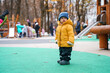 Cute child toddler in a hat and yellow jacket on the playground in autumn
