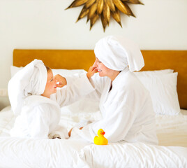 Wall Mural - Happy mother and daughter in bathrobes with cream mask