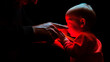 © stateronz - A man touches the face of a small child with his hand in a dark illuminated red light. A deep sense of caring. Early parenting. The bond between father and child. Safety of children