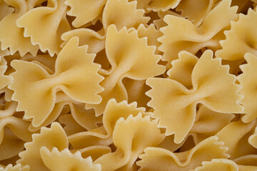 Close-up image showcasing the detailed texture of uncooked farfalle pasta, with a monochromatic yellow theme for culinary appeal.