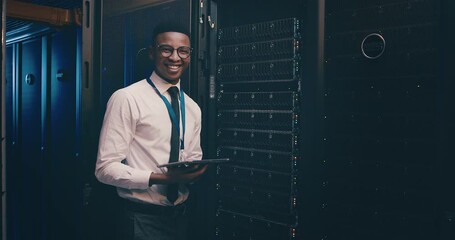 Poster - Portrait of black man in data center with tablet, inspection or network maintenance with engineer in storage update. Tech, system administration or happy technician on digital app in server room.
