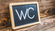 blackboard on wooden wall with the text- wc