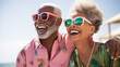 © Positive Click - An elderly couple in sunglasses laughing on a beach.