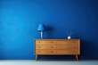  an empty room with a blue wall and a wooden dresser with a blue lampshade on top of it.