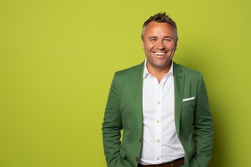 Handsome mature man smiling and looking at camera while standing against green background