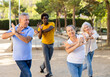 © JackF - Group of cheerful mixed-race and various aged adult people doing aerobics and working out at park on sunny day