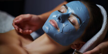 A Young Woman At A Beauticians Appointment. The Specialist Applies A Cream Mask To The Face. Facial Skin Care And Protection. A Girl At The Cosmetologist's Office. Face In Blue Clay. Care Procedure. B