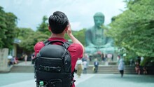 Back View Of Unrecognizable Hispanic Male Tourist Standing In Casual Clothes With Backpack Standing In Front Of Kotoku-in In Buddhist Temple In Kamakura Tokyo In Daylight, Japan