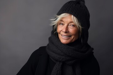 Portrait of a happy senior woman in warm clothing on gray background