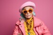 Fashionable senior woman in pink jacket and beret posing against pink background