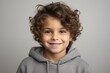 © Inigo - Portrait of a smiling little boy with curly hair over grey background