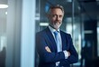 © Gorilla Studio - Portrait of confident mature businessman standing with arms crossed in modern office
