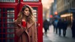 A young fashionable white woman on a London street in front of a red telephone box