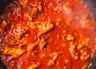 Canvas Print - Chicken meat is stewed in tomato in a frying pan