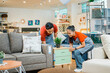© Odua Images - male and female shop assistants work on lifting a desk drawer next to a sofa in a furniture store