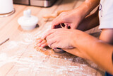 Fototapeta  - Close up hands kneading a dough on a wooden table.