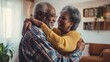 African American senior couple dancing to music together in living room.