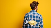Man With Paper Fish On Back Against Yellow Background. April Fool's Day
