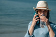 young woman on the beach talking on the mobile phone and drinking a bottle of water