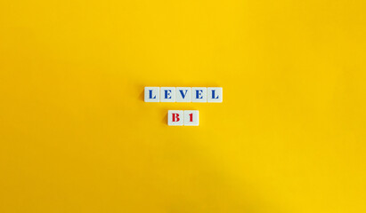 Wall Mural - level b1 word and banner. block letter tiles on yellow background. minimalist aesthetic.