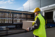 © Halfpoint - Warehouse receiver unloading truck in front of warehouse, carrying cardboard box with delivered items.