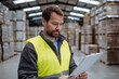 Portrait of warehouseman with clipboard checking delivery, stock in warehouse. Warehouse worker preparing products for shipment.