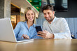 © Westend61 - Happy business colleagues using smart phone at desk