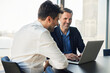 © Westend61 - Happy mature businessman discussing with colleague over laptop at desk