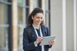© Westend61 - Smiling curly haired businesswoman using tablet PC