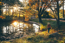 Mature Woman Walking Near Pond In Autumn Park