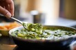 close-up of palak paneer with a spoonful being lifted