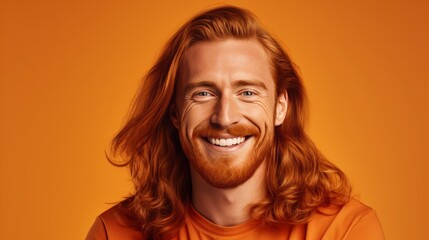 Canvas Print - Handsome elegant sexy smiling Caucasian man with perfect skin and long red hair, on an orange background, banner, close-up.