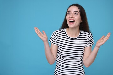 Poster - Portrait of happy surprised woman on light blue background. Space for text