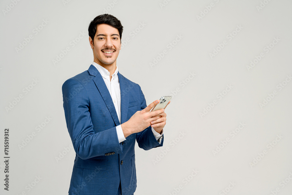 Cheerful businessman in blue suit holds a smartphone, his face ...