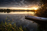 Fototapeta  - cudowny wschód słońca nad jeziorem i łódka przy brzegu