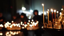 Lit Candles On A Holder, People In Prayer In The Background