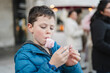 © ADDICTIVE STOCK - A focused young boy enjoying a bite of pink cotton candy in a busy urban blurred background setting