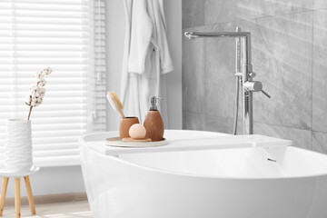 Different personal care products and accessories on bath tub in bathroom