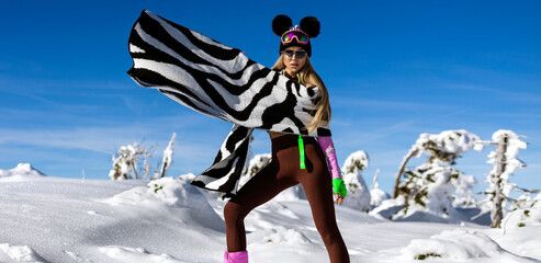 Wall Mural - Beautiful woman wearing winter fashionable jacket and winter boots and is posing in the mountains.